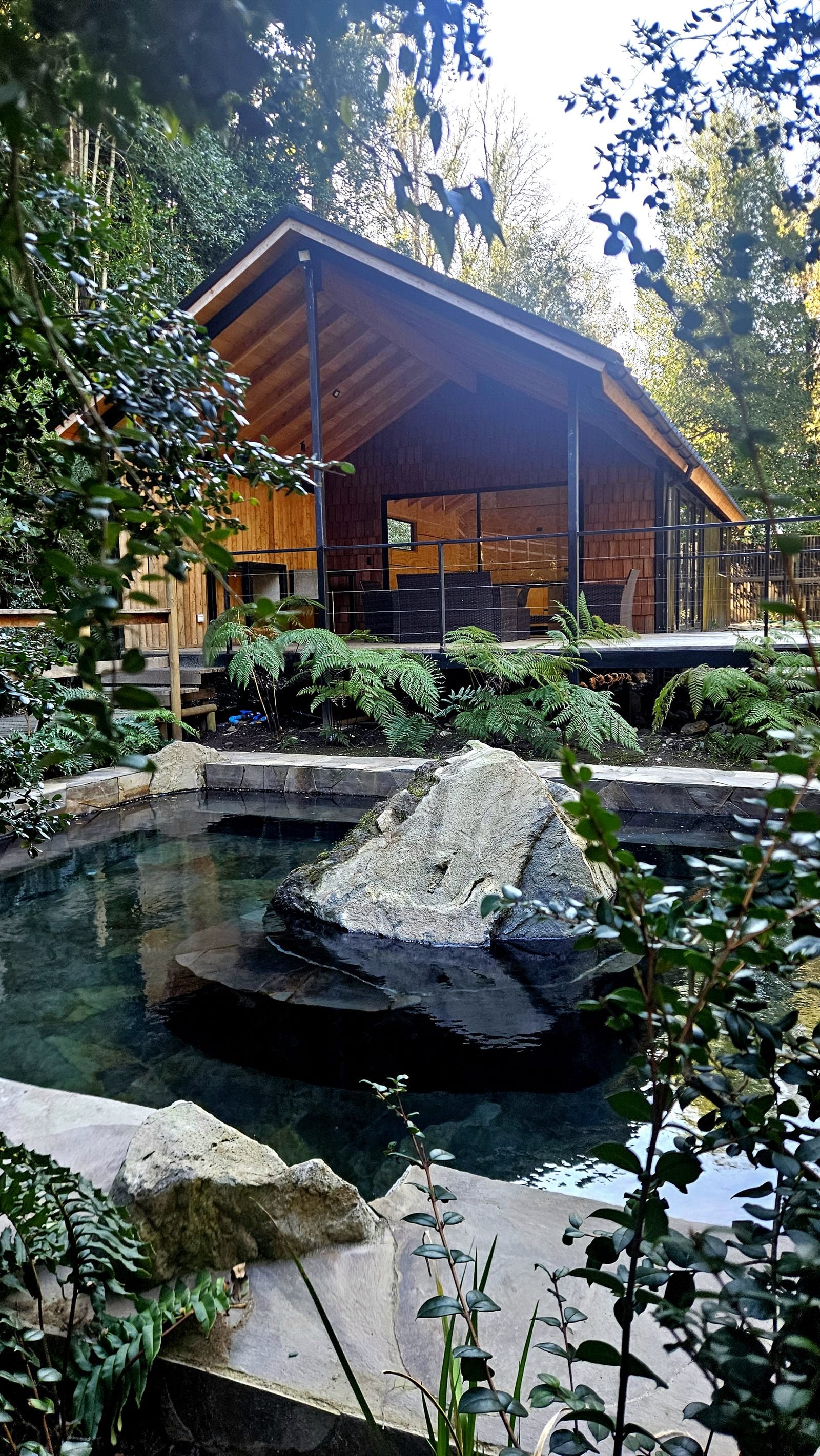 Piscina termal de piedra natural junto al clubhouse de madera