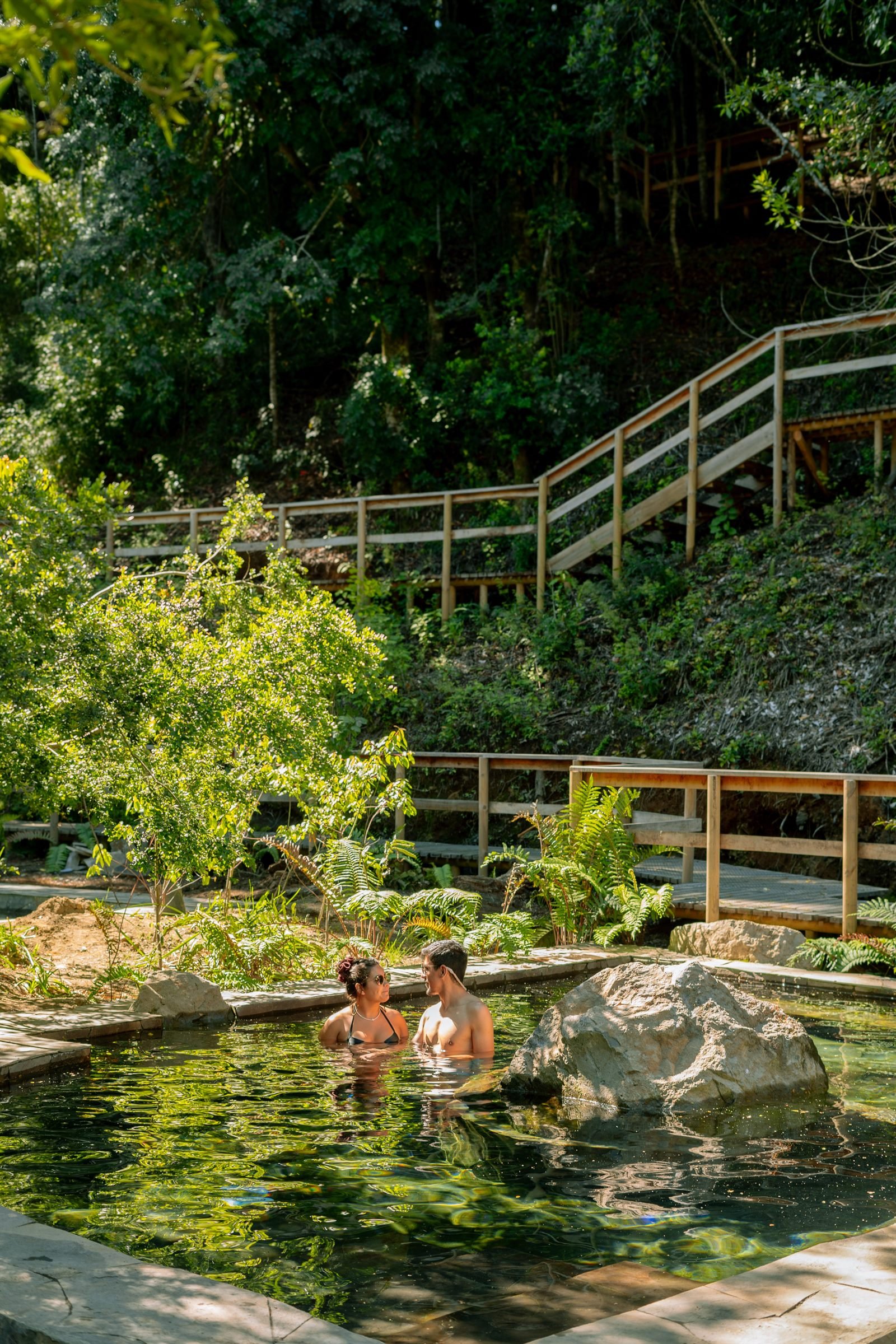 Dos personas disfrutando de las piscinas termales naturales de El Mañío rodeadas de vegetación